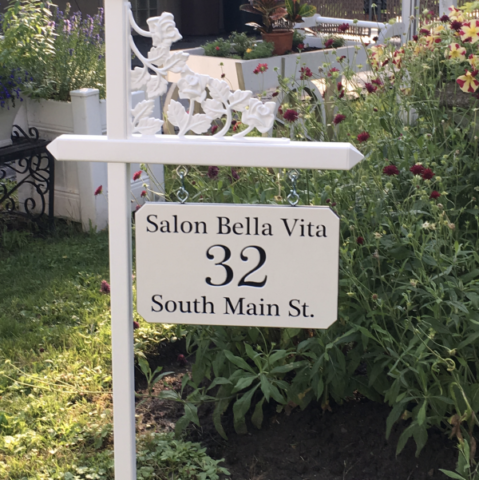 Custom black and white engraved sign made for a local salon on one of our white lawn sign holders with rose scroll