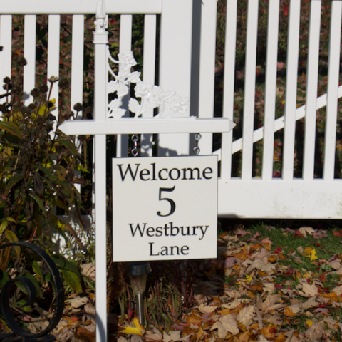 Custom black and white engraved welcome sign on one of our white lawn sign holders with a rose scroll