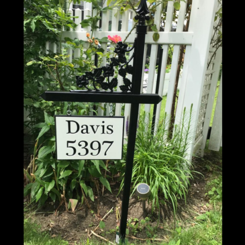 Custom sign with house number and last name using white-black-white color core, hung on a black lawn sign holder with a rose scroll